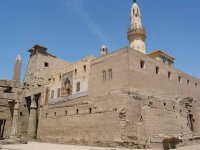 Egypte (مصر) - Époque Pharaonique (العصر الفرعوني) - Nouvel Empire (-1540 à -1069 ; dynasties XVIII, XIX et XX) - Temple d'Amon, Mout et Khonsou à Louxor - Chaque année, au cours de la fête d'Opet qui célèbre la nouvelle crue fertilisante du Nil, Le dieu Amon, résidant à Karnak, gagnait Louxor accompagné de son épouse Mout et de leur fils Khonsou lors d'une procession solennelle. Des barques sacrées transportaient les statues en or représentant les dieux. La construction du temple débuta sous Aménophis III et se poursuivit sous Toutankhamon, Horemheb et Ramsès II. Les romains élevèrent un fort militaire autour du temple que les arabes, plus tard, rebaptisèrent « al-Uqsur » (les Palais) d'où le nom moderne de Louxor - Dans la grande cour de Ramsès II se dresse la mosquée d'Abou al-Haggag. Elle fut érigée au XIIIe siècle sur un soubassement d'église copte. Lors du mouled d'Abou al-Haggag, des barques sont portées en procession dans la ville. Ce rite pourrait être d'origine pharaonique - (Photo, D. van Hoorde) - 05/15 Egypte (مصر) - Époque Pharaonique (العصر الفرعوني) - Nouvel Empire (-1540 à -1069 (...)